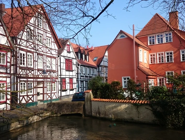Fachwerkhäuser in bunten Farben, entlang eines kleinen Flusses, strahlen Ruhe und Tradition aus.