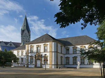 Historisches Gebäude der Stadtbibliothek Paderborn, im Hintergrund ein spitzer Kirchturm.