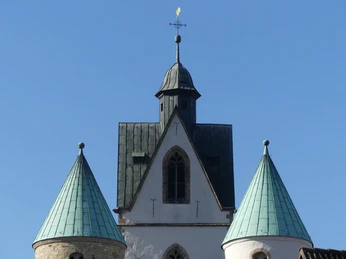 Turmspitzen der Busdorfkirche Drei türkisfarbene Kupferdächer der Busdorfkirche in Paderborn ragen vor strahlend blauem Himmel auf.