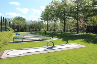 Minigolfanlage im Parkteil Nord Moderner Abenteuergolfplatz auf grüner Wiese unter Bäumen, mit verschiedenen kreativen Bahnen.