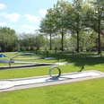 Minigolfanlage im Parkteil Nord Moderner Abenteuergolfplatz auf grüner Wiese unter Bäumen, mit verschiedenen kreativen Bahnen.