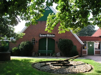 Wanna Heimatmuseum Einladendes Heimatmuseum Wanna: Roter Backsteinbau mit großen grünen Toren unter alten Bäumen.
