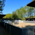 Beach-Soccer-Feld im Parkteil Nord Ein eingezäunter Sandbereich unter freiem Himmel mit mehreren überdachten Pferdeboxen im Hintergrund.