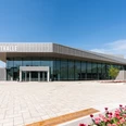 Stadthalle Rheda-Wiedenbrück Moderne Stadthalle in elegantem Grau, umgeben von gepflastertem Platz und blühenden Tulpenbeeten.