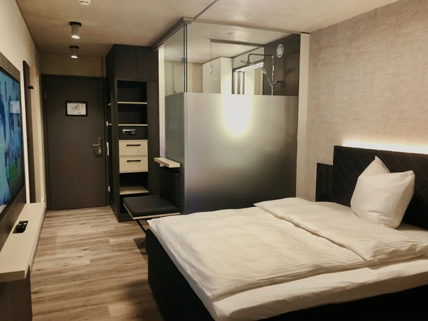 Hotel Zeitgeist - Einzelzimmer Ein modernes Einzelzimmer mit einem großem Bett, elegantem Schreibtisch und stilvollem Bad.
