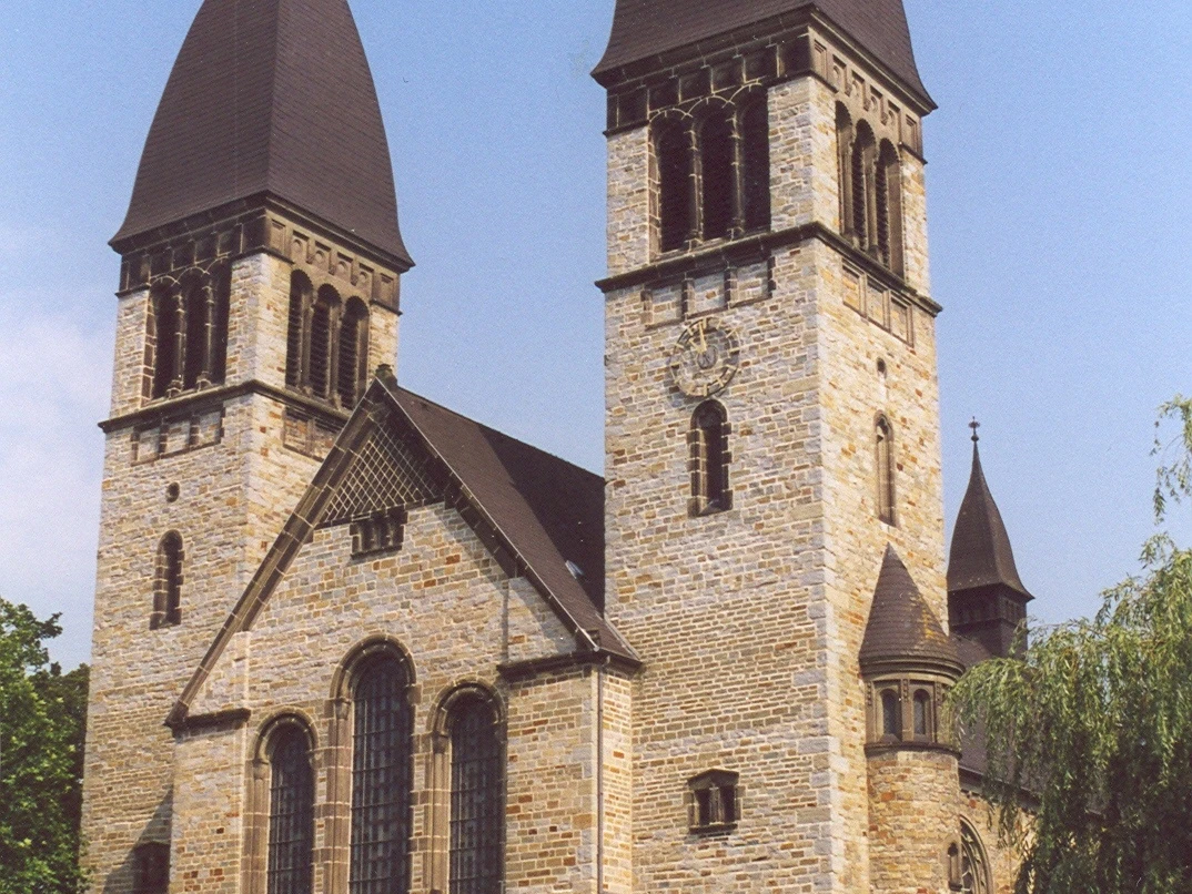 Kirche St. Clemens in Rheda Eine historische Kirche mit zwei markanten Glockentürmen und einem reich verzierten Eingangsportal.