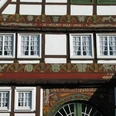 Fachwerkhaus mit reich verzierter Fassade und geschnitzten Holzdetails sowie sechs weißen Fenstern.