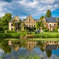 Schloss Ippenburg im Osnabrücker Land Historisches Gebäude mit Spitzgiebeln und bewachsenem Mauerwerk, Park und Teich im Vordergrund.