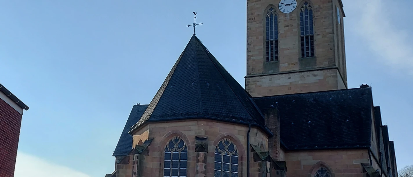 St.-Andreas-Kirche in Emsbüren Sandstein-Kirche mit hohem Turm, spitzem Dach und großen Maßwerkfenstern unter blauem Himmel