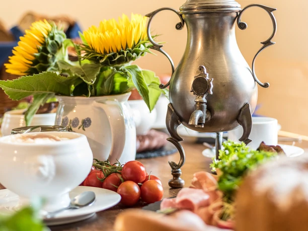Bergische Kaffeetafel Ein gedeckter Tisch mit Kaffeekanne, Sonnenblumen und Frühstücksspeisen.