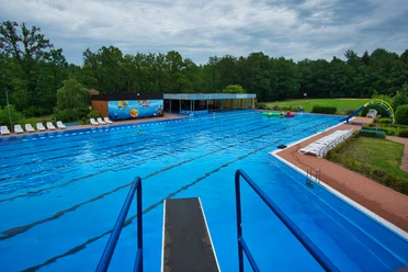 Schwimmerbecken Ein großzügiges, blaues Schwimmerbecken umgeben von Bäumen lädt zum Entspannen und Schwimmen ein.