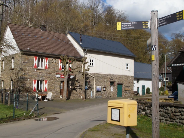 Nespener Mühle <p>Ein ländliches Gasthaus aus Stein mit markanten rot-weißen Fensterläden und einer gelben Postbox.</p>