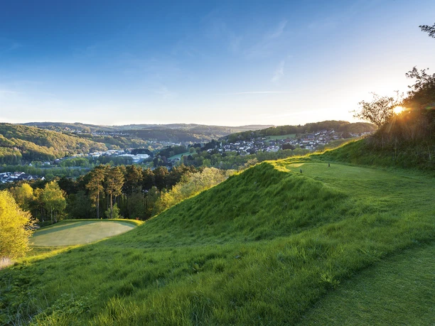Lu_ederich_PAR3653_web.jpg Golflandschaft mit Sonnenuntergang, saftigem Grün, Hügeln und einem malerischen Tal im Hintergrund.