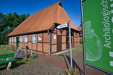 Museum Oldendorf/Luhe Fachwerkgebäude mit rotem Ziegeldach, beschildertem Eingang zum Museum und grünem Gartenschild daneben.