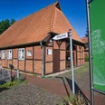 Museum Oldendorf/Luhe Fachwerkgebäude mit rotem Ziegeldach, beschildertem Eingang zum Museum und grünem Gartenschild daneben.