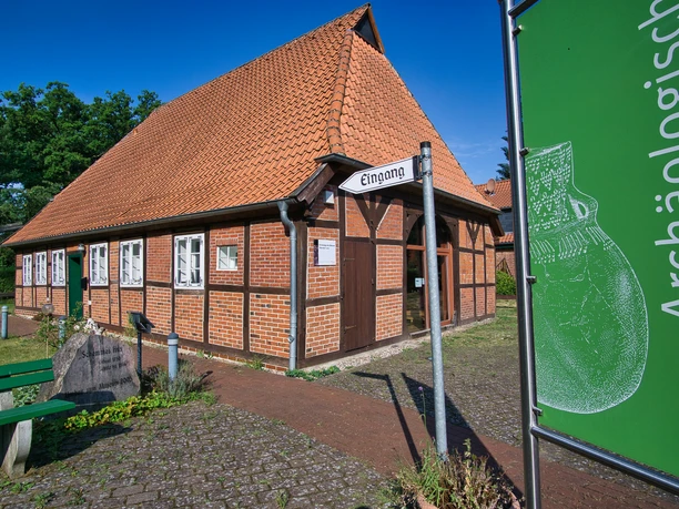 Museum Oldendorf/Luhe Fachwerkgebäude mit rotem Ziegeldach, beschildertem Eingang zum Museum und grünem Gartenschild daneben.