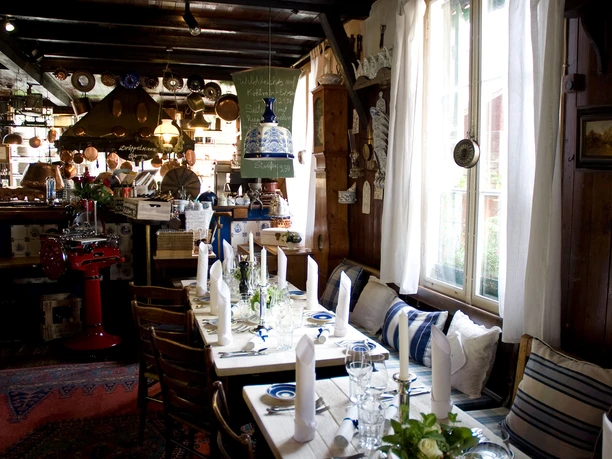 Droeppelminna-restaurant-Bergisch-Gladbach-Herrenstrunden-Joel-Schramm.jpg Gemütliches, traditionelles Gasthausinterieur mit holzvertäfelten Wänden, gedeckter Tisch, warm erleuchtet.