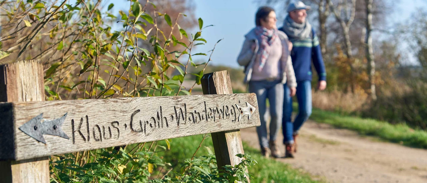 Klaus Groth Wanderweg Holzschild Klaus-Groth-Wanderweg mit Gehenden