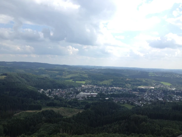 Streifzug Feuer- und Flammeweg <p>Luftaufnahme von Bergneustadt, umgeben von grünen Wäldern und sanften Hügeln unter wolkigem Himmel.</p>