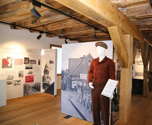 Museum Inselmühle Ausstellungsraum mit Holzdecke, historischen Informationstafeln und Uniformfigur zur Nachkriegszeit