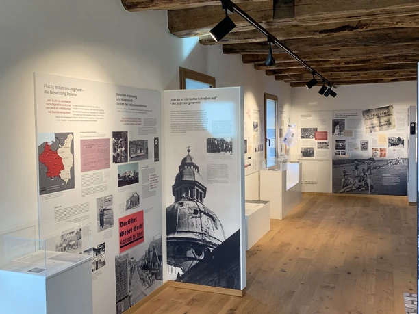 Museum Inselmühle Innenraum des Museums mit Holzdecke, Ausstellungswänden und historischem Bildmaterial zur Stadtgeschichte.