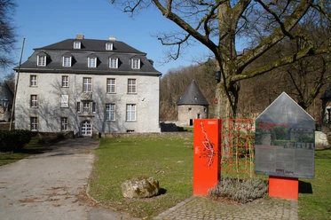 Schloss Hardenberg Das Bild zeigt das historische Haus Kemnade mit Infotafel im Vordergrund an einem sonnigen Tag.