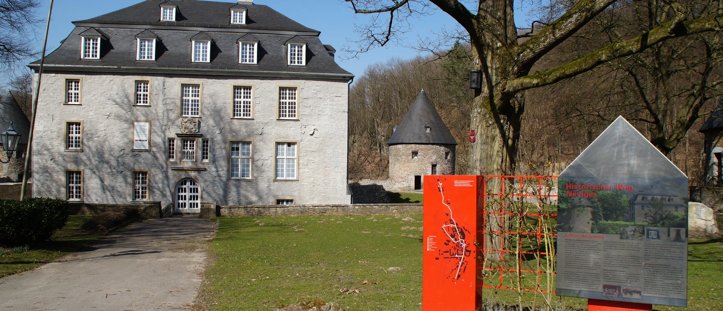 Schloss Hardenberg Das Bild zeigt das historische Haus Kemnade mit Infotafel im Vordergrund an einem sonnigen Tag.