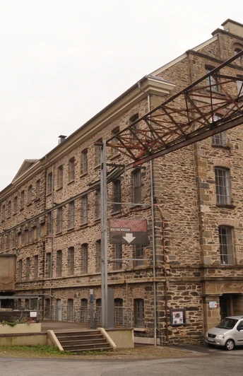 Historisches Fabrikgebäude in Radevormwald mit Backsteinfassade und metallenen Überführung.