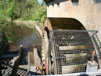 Wassermühle Sudweyhe Historische Wassermühle mit eindrucksvollem Wasserrad, von Bäumen umgeben und an einem Fluss gelegen.