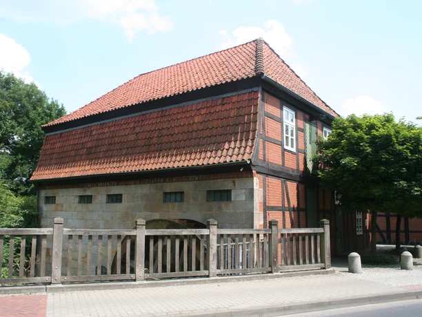 Vakwerkwatermolen met rood pannendak en houten balustrade, harmonieus geïntegreerd in de groene omgeving.