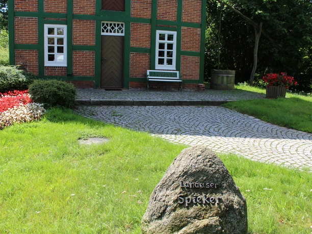 Weyhe Spieker Lahausen Ein traditionelles Fachwerkgebäude mit roten Backsteinen und grünen Rahmen, umgeben von Natur.