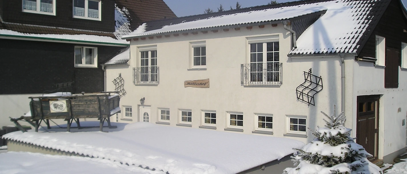 OLYMPUS DIGITAL CAMERA Ein schneebedecktes, zweistöckiges Gebäude mit weißen Fassaden und dunklen Dächern im Winter.