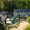 Gammersbacher Mühle Fachwerkhaus mit Biergarten in grüner Umgebung bei Sonnenschein, lädt zum Verweilen ein.