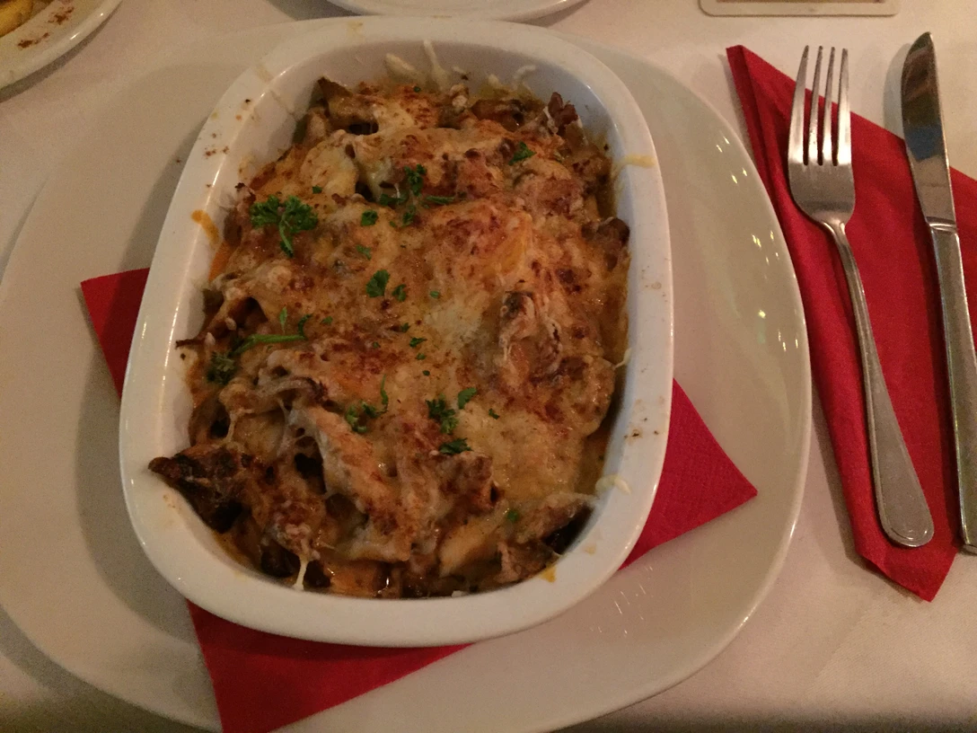 Vollmundiges Gratin aus der griechischen Küche, angerichtet mit frischen Kräutern und geschmolzenem Käse.