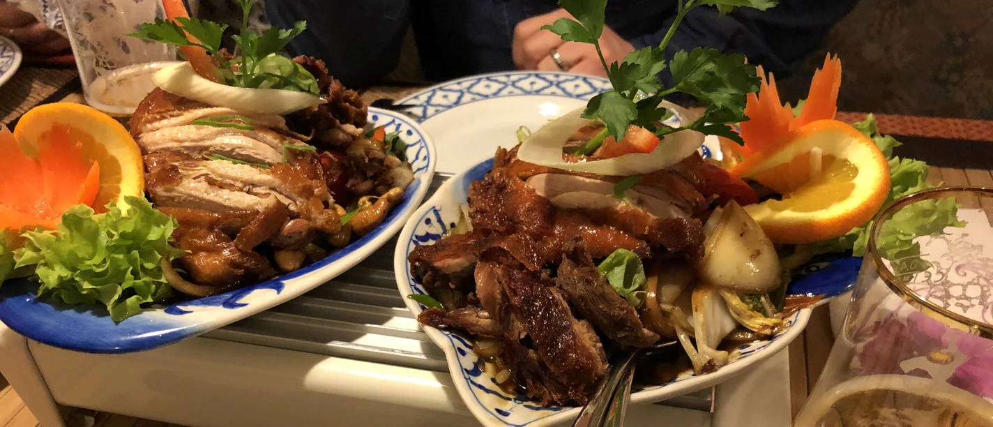 Asiatisches Gericht Ein buntes, reichhaltiges asiatisches Gericht mit knusprigem Fleisch, frischem Gemüse und Zitrusdeko.