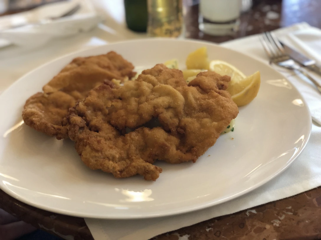 Schnitzel Zwei knusprig panierte Schnitzel auf einem weißen Teller, garniert mit Zitronenscheiben.
