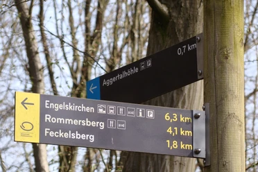 Wegweiser Wegweiser im Wald zeigt Entfernungen zur Aggertalhöhle, Engelskirchen, Rommersberg und Feckelsberg.