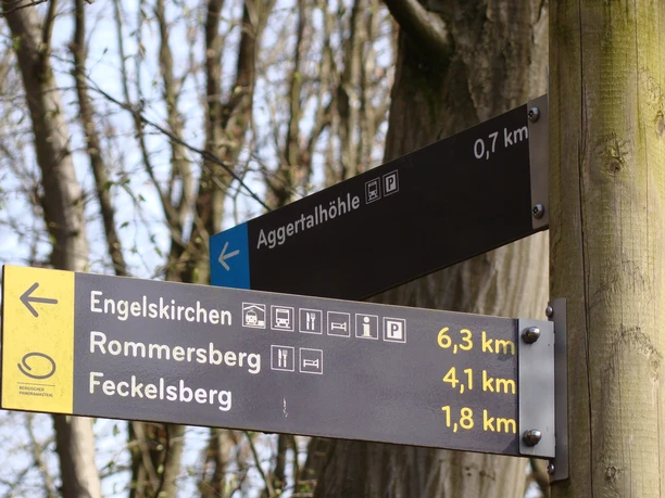 Wegweiser Wegweiser im Wald zeigt Entfernungen zur Aggertalhöhle, Engelskirchen, Rommersberg und Feckelsberg.