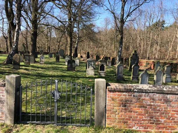 Jüdischer Friedhof Liebenau Jüdischer Friedhof Liebenau mit historischen Grabsteinen umgeben von hohen Bäumen und einer Backsteinmauer.