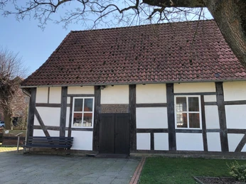 Kapelle Röhden Schlüsselburg Fachwerk-Kapelle mit rotem Ziegeldach, bemalte Fensterläden und einladende Grünfläche im Vordergrund.