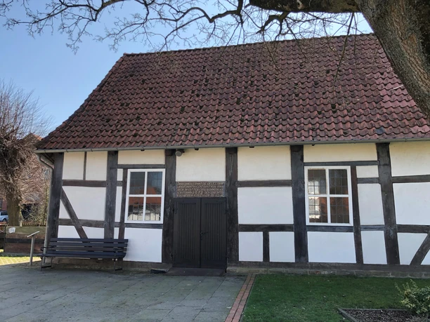 Kapelle Röhden Schlüsselburg Fachwerk-Kapelle mit rotem Ziegeldach, bemalte Fensterläden und einladende Grünfläche im Vordergrund.