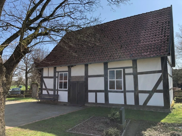 Kapelle Röhden Schlüsselburg Schlichte Fachwerkkapelle mit hellem Anstrich und roten Dachziegeln, umgeben von grüner Natur.