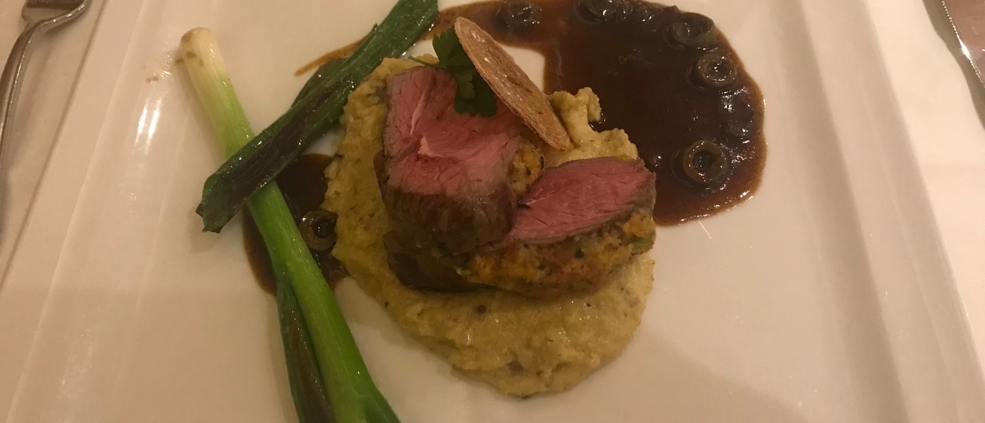 Malse roze ossenhaas op aardappelpuree, versierd met prei en hartige champignonsaus.