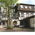 Biesenbach Fachwerkhaus mit Satteldach und angrenzendem Gebäude, davor ein Baum und ein Motorrad.