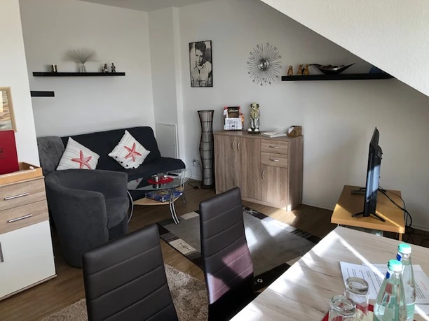 Wohnraum1.jpg Gemütliches, modern eingerichtetes Wohnzimmer mit schwarzem Sofa, Flachbild-TV und stilvollen Details.