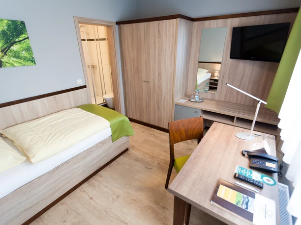 Hotel-Restaurant Lüdenbach Modern eingerichtetes Hotelzimmer mit Einzelbett, Schreibtisch, TV, schlichter Dekor und hellem Holzmobiliar.