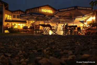 Hotel - Restaurant Lüdenbach Ein stimmungsvoll beleuchteter Biergarten vor einem Hotel bei Dämmerung. Gemütliche Atmosphäre.