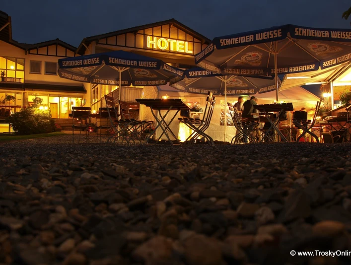 Hotel - Restaurant Lüdenbach Ein stimmungsvoll beleuchteter Biergarten vor einem Hotel bei Dämmerung. Gemütliche Atmosphäre.