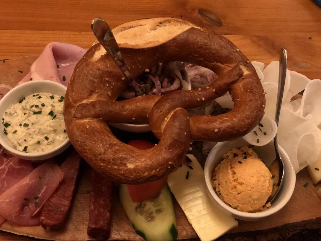 Brezel Herzhafte Brotzeitplatte mit Brezel, regionalen Aufschnitten und Käse, begleitet von würzigen Dips.Hearty snack platter with pretzels, regional cold cuts and cheese, accompanied by spicy dips.Hjertelig snackplatte med saltkringler, regionalt pålæg og ost, ledsaget af velsmagende dips.Hartige snackschotel met pretzels, regionale vleeswaren en kaas, vergezeld van hartige dipsausjes.
