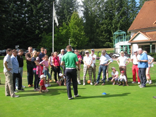 Teilnehmer Schnupperkurs mit Pro Sebastian Neuhaus Eine Gruppe von Menschen hört einem Golflehrer auf einem Golfplatz aufmerksam zu.